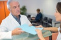 Confident old doctor giving medical records to female assistant Royalty Free Stock Photo