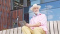 Older man engrossing in tablet while sitting on wooden bench