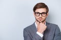 Confident pensive handsome bearded young man is looking away wearing suit and glasses. touching his chin Royalty Free Stock Photo