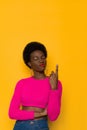 Confident And Perky Young Black Woman In Neon Color Pink Sweater Is Pointing Up