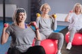 Confident persistent women exercising with dumbbells