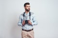 Confident photographer. Handsome young man in casual clothes is holding camera and looking away while standing on a grey Royalty Free Stock Photo