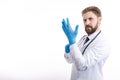 Confident Physician in White Smock Putting on Blue Medical Gloves