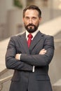 Confident pleasant calm businessman standing outside office smiling and crossed hands. professional man after made deal