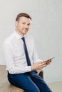 Confident pleased young male entrepreneur in luxury formal clothes, reads recieved text message from colleague on modern tablet co