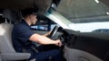 Confident policeman sitting in patrol car, turning ignition keys to drive