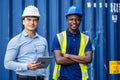 Confident port manager and engineer while stand crossed arms and smiling at freight containers Royalty Free Stock Photo