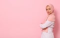 Confident portrait of Arabic muslim beautiful woman with attractive look and gaze, wearing a pink hijab and standing sideways