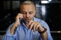 Confident portrait of handsome middle aged man talking on mobile phone, holding a pen in his hand Royalty Free Stock Photo