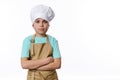 Confident portrait of handsome teenage boy dressed as baker confectioner in chef hat and beige apron, isolated on white