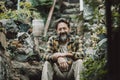 Confident portrait of mature young man alone sitting in the garden and looking on camera smiling. Adult male people having relax Royalty Free Stock Photo