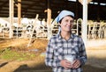 Confident female milker approvingly demonstrating milk on dairy farm Royalty Free Stock Photo