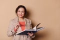 Confident positive middle-aged multi-ethnic female teacher, holding eyeglasses and book, smiling looking at camera