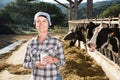 Confident female milker approvingly demonstrating milk on dairy farm Royalty Free Stock Photo