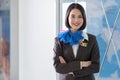 Confident pretty flight attendant/stewardess standing and crossed arm in front of the gate entrance. Smile and welcome on the