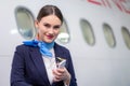 Confident pretty flight attendant/stewardess standing and smile at the passenger. Waiting for the passenger to board in a front