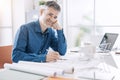 Confident professional architect posing in his office and smiling at camera, he is sitting at desk and working on a building Royalty Free Stock Photo