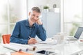 Confident professional architect posing in his office and smiling at camera, he is sitting at desk and working on a building Royalty Free Stock Photo