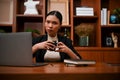 Confident and professional Asian businesswoman holding a coffee cup, sitting at her office desk Royalty Free Stock Photo