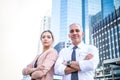 Confident professional businessman and businesswoman standing arms crossed in front of an office building at business center in Royalty Free Stock Photo