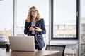 Confident professional woman using earphone and smartphone and having video call in a modern office Royalty Free Stock Photo