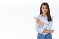 Confident professional young woman in blue blouse pointing finger upper left corner and looking at camera persuade