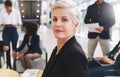 Confident and proud of my team. Cropped portrait of an attractive mature businesswoman sitting while her colleagues work Royalty Free Stock Photo