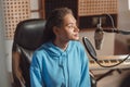 Confident radio presenter, anchor woman sitting in front of a professional microphone in professional recording studio Royalty Free Stock Photo