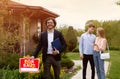 Confident realtor and happy young couple near beautiful country house outside Royalty Free Stock Photo