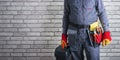 Confident repairman in uniform with toolbox over brick wall with copy space.. Repair concept.