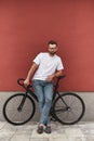 Confident rider. Handsome and young man with stubble in casual clothes and eyeglasses leaning at his bicycle and looking Royalty Free Stock Photo