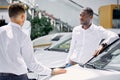 Confident salesman talk about characteristics of car to customer man