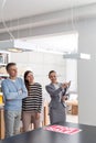 Confident saleswoman gesturing to couple while standing in apartment