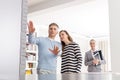 Confident saleswoman looking at couple discussing in apartment