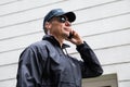 Confident Security Guard Listening To Earpiece Against Building