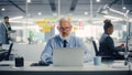 Confident Senior Businessman Using Laptop Computer in Modern Office with Colleagues. Stylish Royalty Free Stock Photo