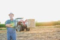 Confident senior farmer standing with arms crossed against tractor in field Royalty Free Stock Photo