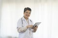 Confident senior female doctor happy using tablet computer standing in clinic. Royalty Free Stock Photo