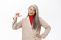 Confident senior woman, businesswoman in suit pointing finger at herself and smiling with self-assured face expression Royalty Free Stock Photo