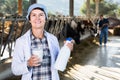 Confident senior woman veterinarian approvingly demonstrating milk on dairy farm Royalty Free Stock Photo