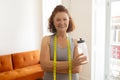 Confident senior woman wearing tape measure and holding water bottle