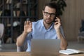 Confident serious businessman in glasses talking on phone, using laptop Royalty Free Stock Photo