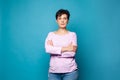 Confident serious mature woman with crossed arms standing against blue studio wall background Royalty Free Stock Photo