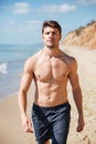 Confident shirtless young man walking along the beach Royalty Free Stock Photo