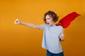 Confident short-haired girl posing in red superhero cloak. Studio shot of brave young woman in superwoman costume..