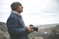 Young man, travel photographer holding professional digital camera, capturing beautiful view while hiking in mountains Royalty Free Stock Photo