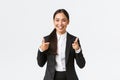 Confident smiling asian saleswoman in black suit showing thumbs-up, guarantee quality of product or providing best