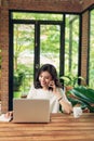 Confident smiling asian woman using phone and laptop Royalty Free Stock Photo