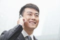 Confident, smiling businessman on his mobile phone outdoors in Beijing, China