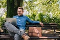 Confident smiling professional analyzing business plan on laptop at park bench Royalty Free Stock Photo